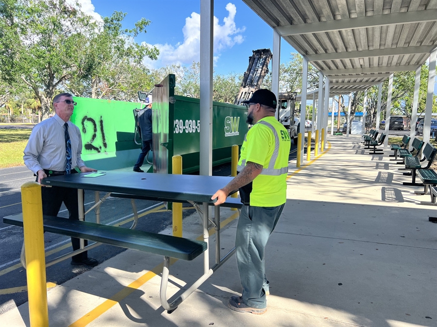 Principal Mangan helps Southwest Waste employee unload a picnic table