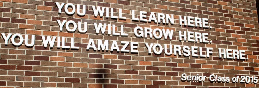 Picture of brick wall what a quote that reads "You will learn here, You will grow here. You will amaze yourself here. Class of 2015."