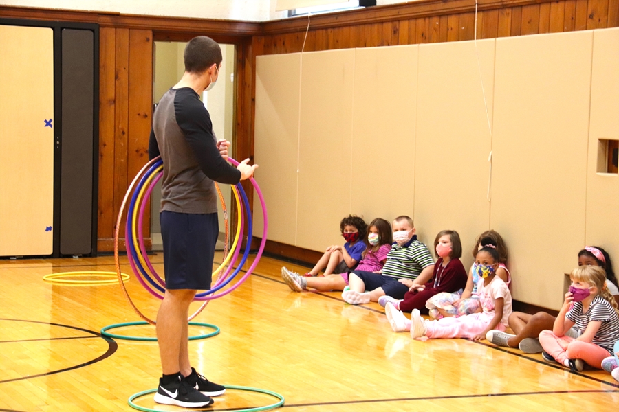 Gym teacher is handing out hoola hoops in class to play with